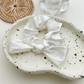 Detail shot of a white satin scrunchie with a bow on a ceramic dish with rustic decor - White