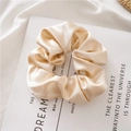 Close-up of champagne silk satin scrunchie with soft pleats on a minimalist background - Champagne