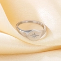 Macro view of polished silver starburst signet ring on champagne silk fabric - US 10 / Steel