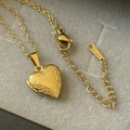 Detalle de collar relicario de corazón vintage con relieve floral dorado y cadena fina - Oro de 18K