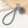 Détail d'un porte-clés pompon gris en fausse fourrure avec lanière tressée et anneau argenté - Bleu marine