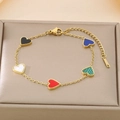 Detalle macro de la pulsera dorada con dijes de corazones de colores en un cojín - Multicolor (KB187178-BI)