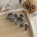 Macro detail of wave-shaped acetate hair claw clip with marble texture on wooden tray - Ink