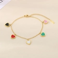 Macro shot of 18K gold plated heart bracelet with colorful enamel pendants on silk - Colorful
