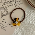 Detail view of tortoiseshell flower hair tie with pearl accent on decorative card - Dark Leopard Print