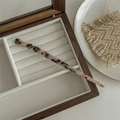 Macro view of leopard print acetate hair claw clip resting in a wooden jewelry box - Hair Stick