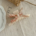 Detail van een crème haarklem van acetaat met een roze en witte marmeren strik erop - Roze