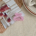 Detail of a small pink heart-shaped hair claw clip with French text on a woven mat - Lavender