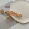 Détail d'un peigne à dents larges orange translucide avec motif marguerite sur assiette - Orange