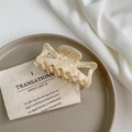Detailed close-up of beige marble texture acetate hair claw clip on a ceramic plate - Off-white
