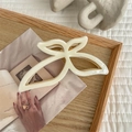 Detail of elegant cream butterfly hair claw clip with golden metal spring on wooden tray - Cream White