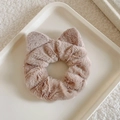 Detailed close-up of light brown plush cat ear scrunchie on a white textured tray - Camel