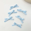 Détail de six barrettes à nœuds en ruban de satin bleu clair sur un fond blanc pur - Bleu (Lot de 6)