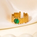 Macro-opname van een goudkleurige open ring met groene edelsteen op beige zijden stof - Smaragdgroene Steen Stijl (R0850)