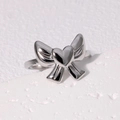Anillo de lazo plateado con corazón en acero inoxidable, estilo minimalista fondo blanco - Diseño con Lazo e Incrustación de Corazón / Color Acero