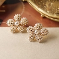 Pendientes de flores de perlas de lujo francés sobre fondo de papel beige texturizado - Flor de Cinco Pétalos de Perla Dorada