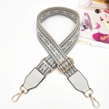 Detailed view of gray and white ethnic embroidery bag strap with gold metal hardware - Gray/White + White Leather