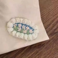 Detail of handmade oval embroidery hair clip featuring a pink flower on blue background - Oval Flower Hair Clip