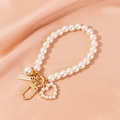 Close-up of pearl heart keychain with gold hardware on soft pink silk fabric background - Heart Style