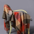 Plaid cashmere blend scarf with long tassels draped on a modern wooden chair - Orange Red Brown Grey Plaid