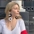 Outdoor shot of a model wearing large black and white acrylic sunflower earrings with a heart necklace - Black and White Pattern