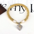 Detailed macro view of gold beaded bracelet featuring freshwater pearls and starburst charm - Star Shield Pendant (Style 1)