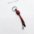 Detailed view of a brown braided leather keychain with silver metal rings and ends - Dark Brown