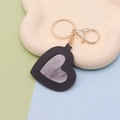 Macro detail of black PU leather heart keychain with mirror and gold metal ring on tray - Black Heart