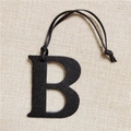 Macro shot of black leather letter B bag charm with textured finish and leather cord - Letter B Black