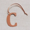 Macro detail of a brown Epsom leather letter C bag charm with matching strap - Letter C Brown