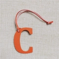 Detail of orange pebble leather letter C handbag charm with matching strap - Letter C Orange