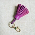 Detailed close-up of purple genuine leather tassel pendant with gold metal lobster clasp - Deep purple