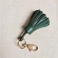 Dettaglio portachiavi con nappa in pelle verde scuro, anello e chiusura in metallo dorato - Verde Scuro