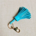 Blue leather tassel keychain with golden spring hook on beige textured fabric - Sky Blue