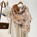 Detailansicht des Jacquard-Blumenmusters und der Fransen an einem dicken Winterschal - Orange
