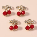 Dettaglio di quattro ciondeli a ciliegia rossa in lega con foglie dorate e strass lucidi - Combinazione fiocco