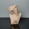 Elegant pearl necklace with green gemstone pendant on black half-face model bust - Nude
