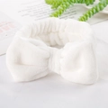 Close-up of a white plush coral fleece headband with a large soft bow for skincare - White