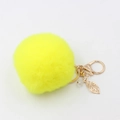 Dettaglio di un portachiavi a pompon giallo con ciondolo a foglia dorata e perla - Giallo