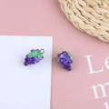 Dettaglio macro di un ciondolo a uva in resina viola con foglia verde e anello in metallo - Uva