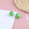 Macro detail of two green apple resin charms with silver hooks on pink background - Green Apple