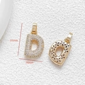 Detalle de colgante letra D chapado en oro con circonitas y reverso con diseño floral calado - Letra D
