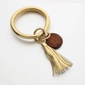 Detail of gold leather bracelet keychain with PU tassel and brown wooden pendant - Gold