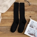 Chaussettes hautes en polaire corail noire sur fond bois rustique avec décor cosy - Noir