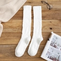 Chaussettes montantes en polaire corail blanche sur un fond de table en bois rustique - Blanc