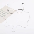 Detail of metal eyewear chain with silver cross on semi-rimless frames over white background - Silver