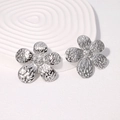 Silver flower stud earrings with hammered metal texture on white artistic pedestal - Steel