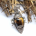 Close-up of a drop-shaped tiger eye stone pendant in a silver vintage filigree frame - Tiger's Eye