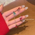 Detailansicht asymmetrischer Weihnachtsohrringe mit kletterndem Weihnachtsmann und Baum - Weihnachtsbaum & Schlitten Stil