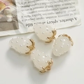 Detailed view of milky white resin strawberry pendants with pearls and gold metal leaves - White